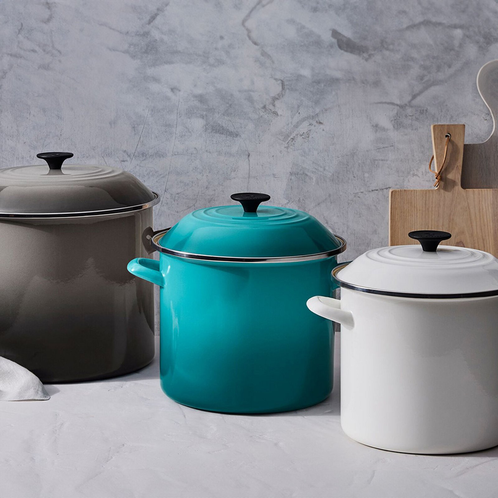 1 photo of 3 Le Creuset stock pots, 1st in black, 2nd in aqua, and 3rd in white.